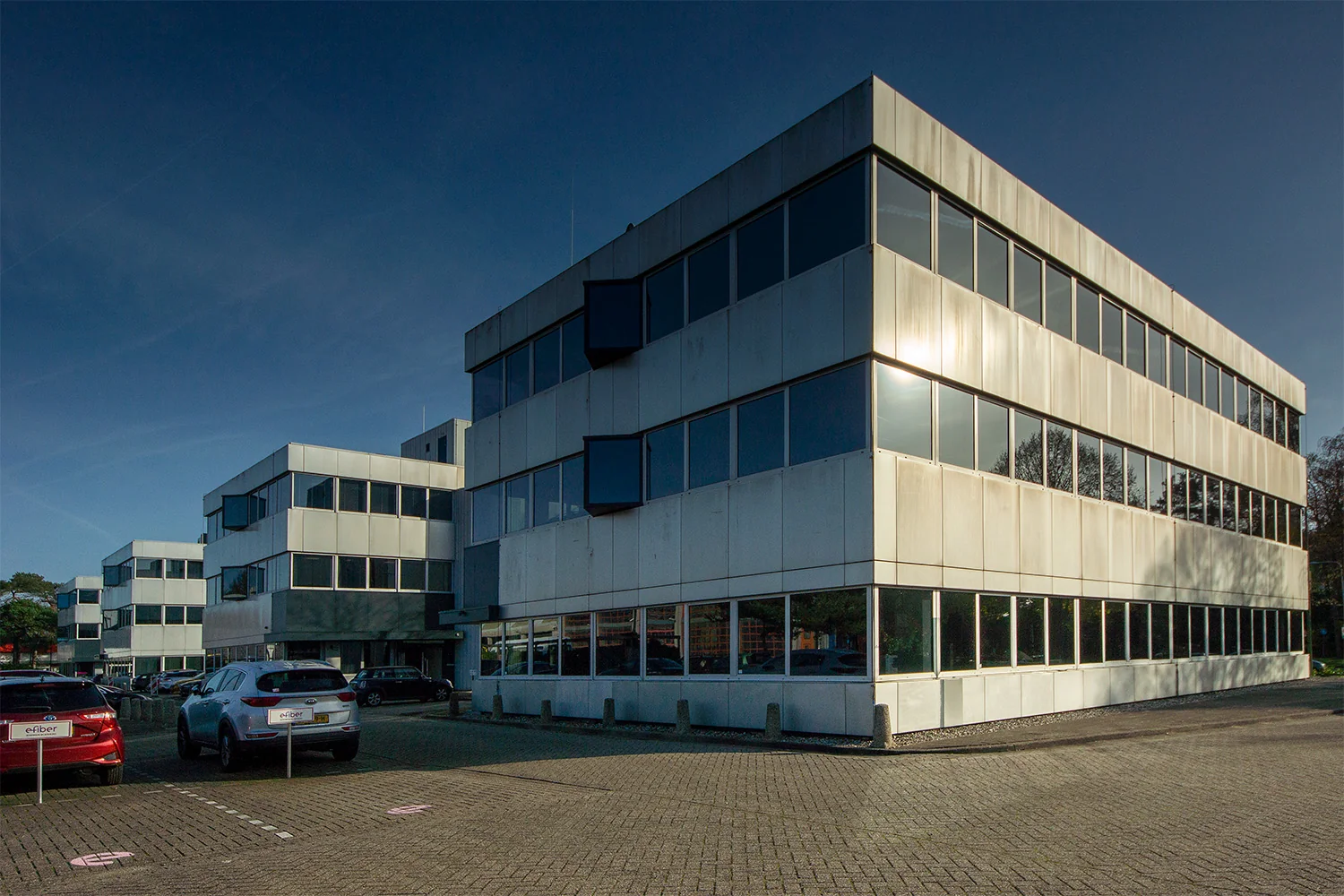 Modern kantoorpand aan de Huis ter Heideweg met meerdere verdiepingen en parkeerplaatsen op de voorgrond.